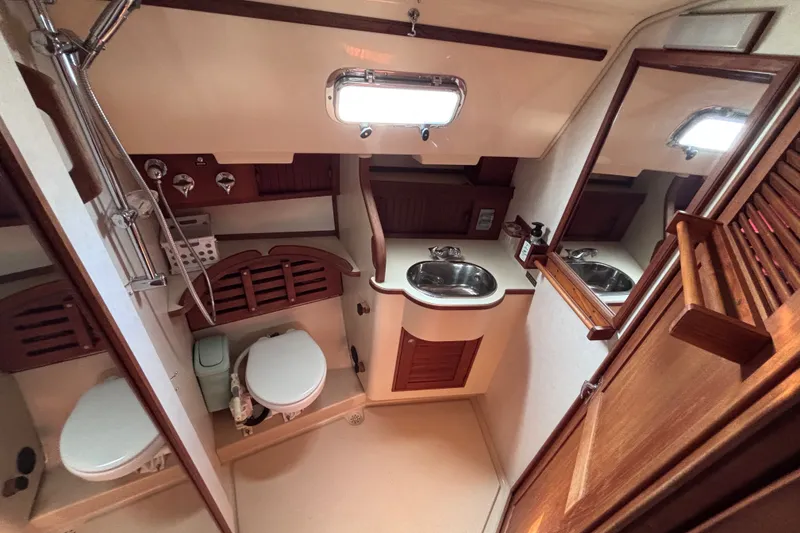 Slide: The Image of Island Packet 380 yacht bathroom, featuring a sink, toilet, and wooden cabinetry, 2000 model. - 29