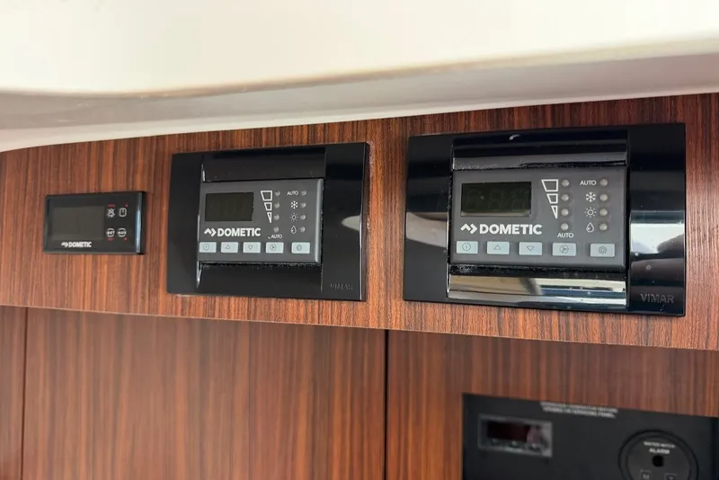 Slide: The Image of Dometic control panels on wood paneling in a Pursuit DC 326 Dual Console boat. - 46