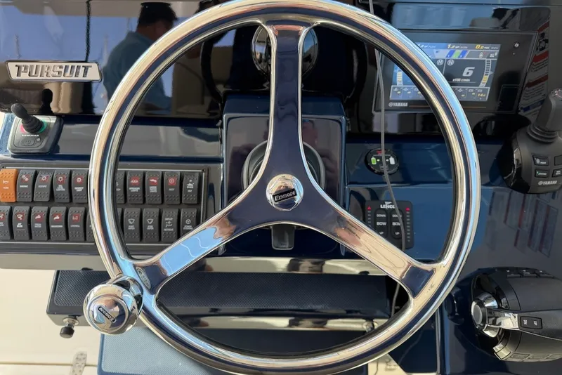 Slide: The Image of The image shows the helm of a 2021 Pursuit DC 326 Dual Console boat. - 32