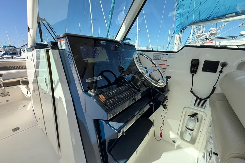 Slide: The Image of The image shows the helm of a 2021 Pursuit DC 326 Dual Console in a marina. - 30