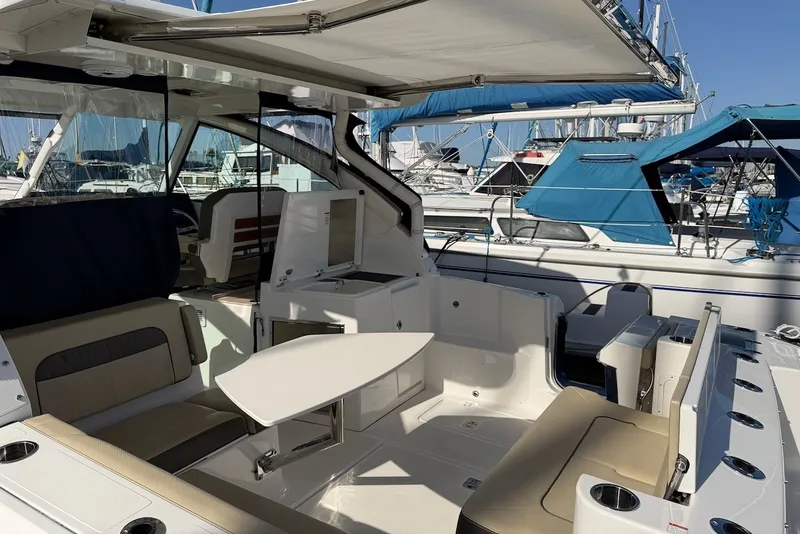 Slide: The Image of The 2021 Pursuit DC 326 Dual Console features an open cockpit with beige seating and a table. - 12