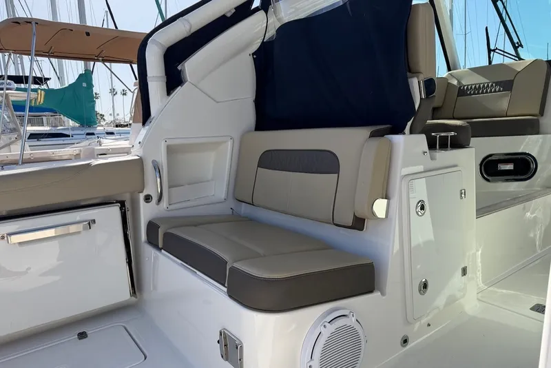Slide: The Image of The 2021 Pursuit DC 326 Dual Console features a sleek seating area with gray upholstery and storage. - 16