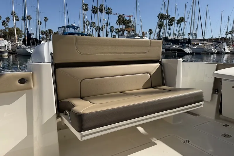 Slide: The Image of A beige and brown bench seat on a boat, surrounded by a marina with sailboats. - 15
