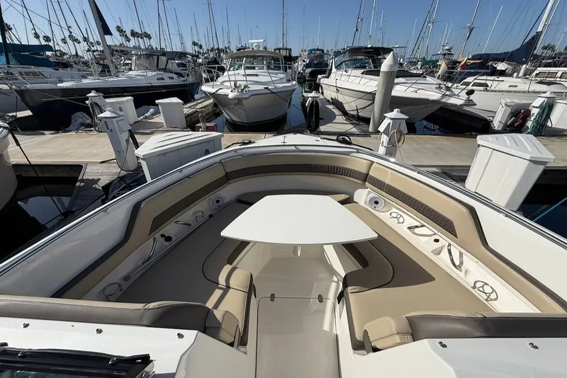 Slide: The Image of 2021 Pursuit DC 326 Dual Console docked, featuring beige seating and a table in the bow area. - 41