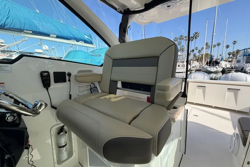 Slide: The Image of 2021 Pursuit DC 326 Dual Console: Comfortable helm seat with padding, surrounded by yachts in a marina. - 28