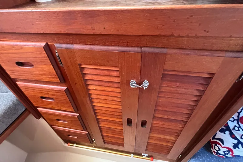 Slide: The Image of Wooden cabinetry inside a 1985 Catalina 30 sailboat, featuring drawers and louvered doors. - 27