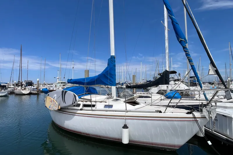 The Image of 1985 Catalina 30 sailboat docked in a marina under a clear blue sky. - 0