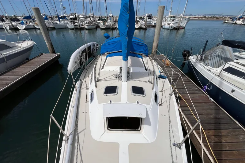 Slide: The Image of 1985 Catalina 30 sailboat docked at marina, surrounded by other boats. - 2