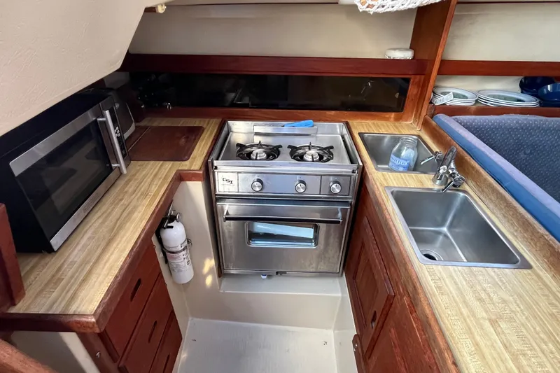 Slide: The Image of Compact kitchen in a 1985 Catalina 30 sailboat with stove, sink, and microwave. - 19