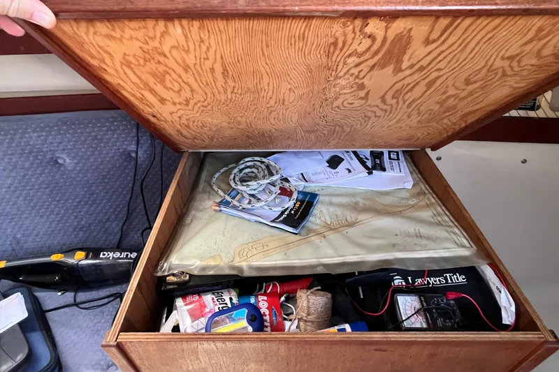 Slide: The Image of Open storage compartment in 1985 Catalina 30 sailboat with various items and documents. - 32