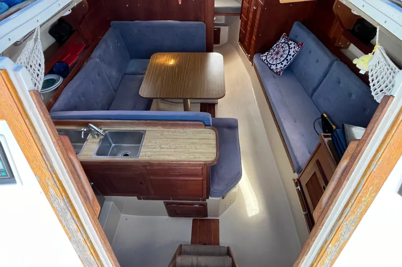 Slide: The Image of Interior of a 1985 Catalina 30 sailboat with cozy seating and compact kitchen area. - 14