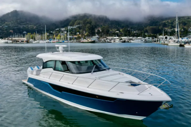 Slide: The Image of 2027 Tiara Yachts 48 LE cruising in scenic marina with misty hills. - 15