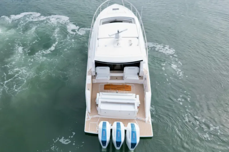 Slide: The Image of 2027 Tiara Yachts 48 LE cruising on water, rear view with triple engines. - 34