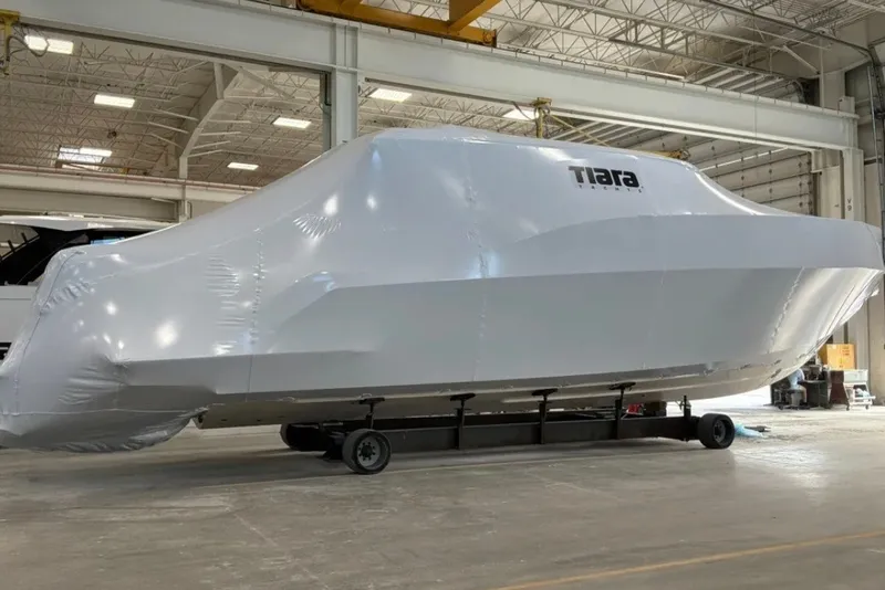 Slide: The Image of 2027 Tiara Yachts 48 LE wrapped in protective cover inside a spacious warehouse. - 39