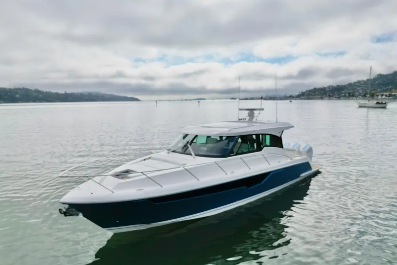 Slide: The Image of 2027 Tiara Yachts 48 LE cruising on calm waters under a cloudy sky. - 14