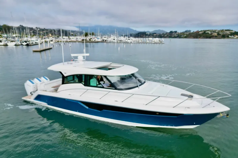 The Image of 2027 Tiara Yachts 48 LE cruising in a marina with scenic background. - 0