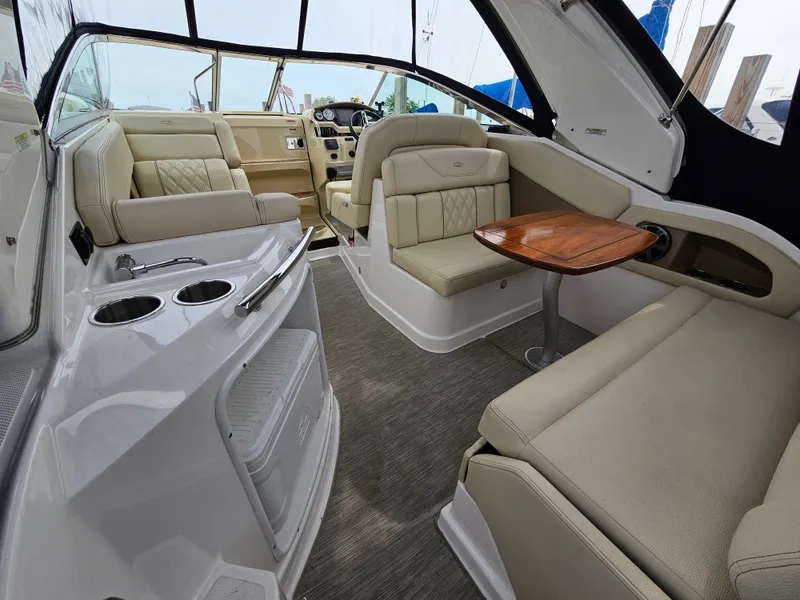 Slide: The Image of Interior of a 2019 Regal 28 Express with beige seating and a wooden table. - 2