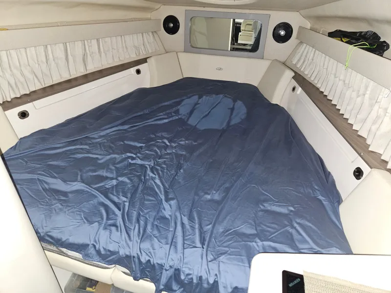 Slide: The Image of Cabin of the 2019 Regal 28 Express with a large bed and curtains. - 12