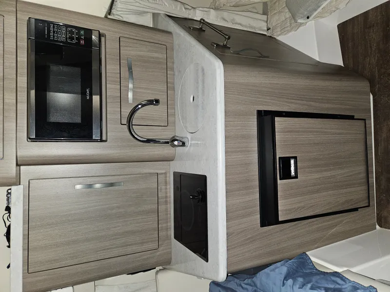 Slide: The Image of The galley of a 2019 Regal 28 Express with a microwave, sink, and refrigerator. - 10