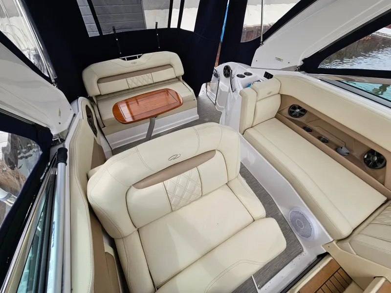 Slide: The Image of Interior of a 2019 Regal 28 Express with beige leather seating and a wooden table. - 1