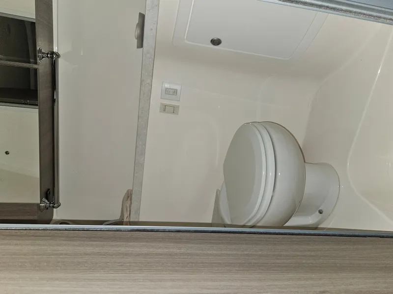 Slide: The Image of The image shows a bathroom with a toilet and mirror in a Regal 28 Express boat. - 15
