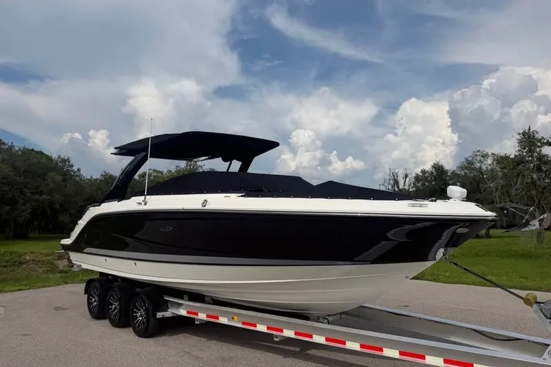 Slide: The Image of Ein 2019er Sea Ray SLX 310 Outboard auf einem Anhänger, mit schwarzem Rumpf und weißem Deck. - 19
