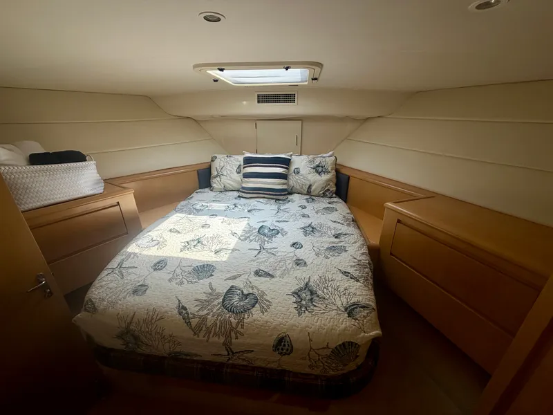 Slide: The Image of Cabin of the 1999 Hatteras 52 Cockpit Motor Yacht with a cozy bed and storage space. - 26