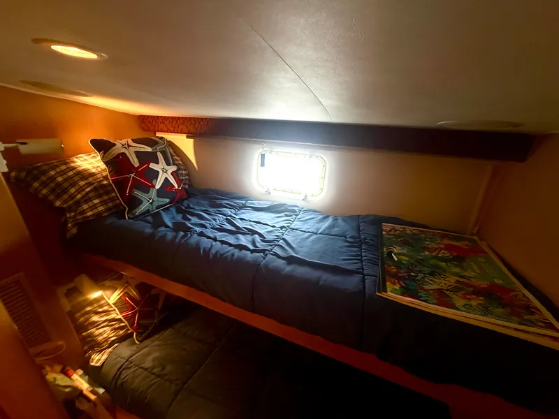 Slide: The Image of Cabin with bunk beds, blue bedding, and decorative pillows, lit by a small window. - 25
