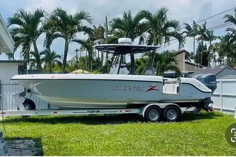 Slide: The Image of 2004 Donzi 29 ZF Open boat on trailer, parked in a tropical yard. - 0