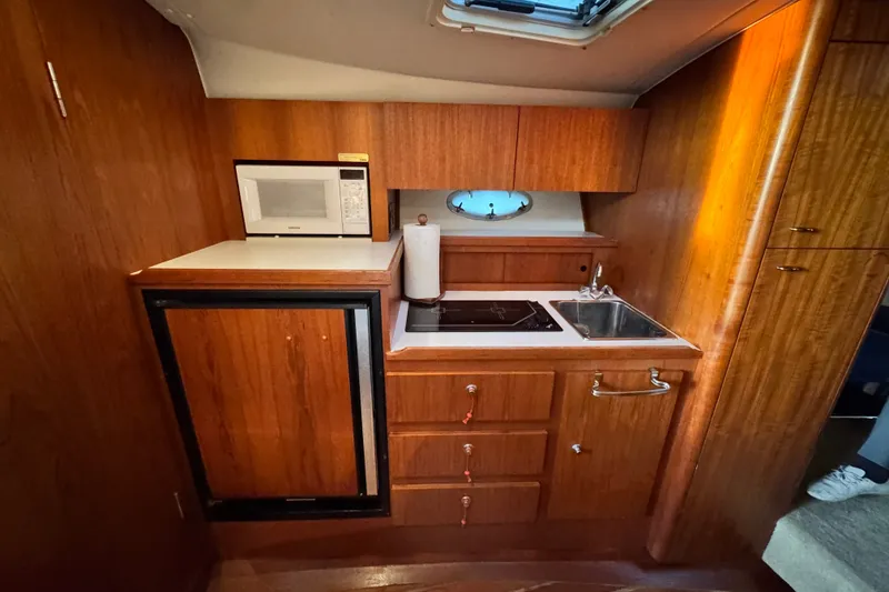 Slide: The Image of 2001 Tiara Yachts 3100 Open galley with microwave, sink, and wooden cabinetry. - 19