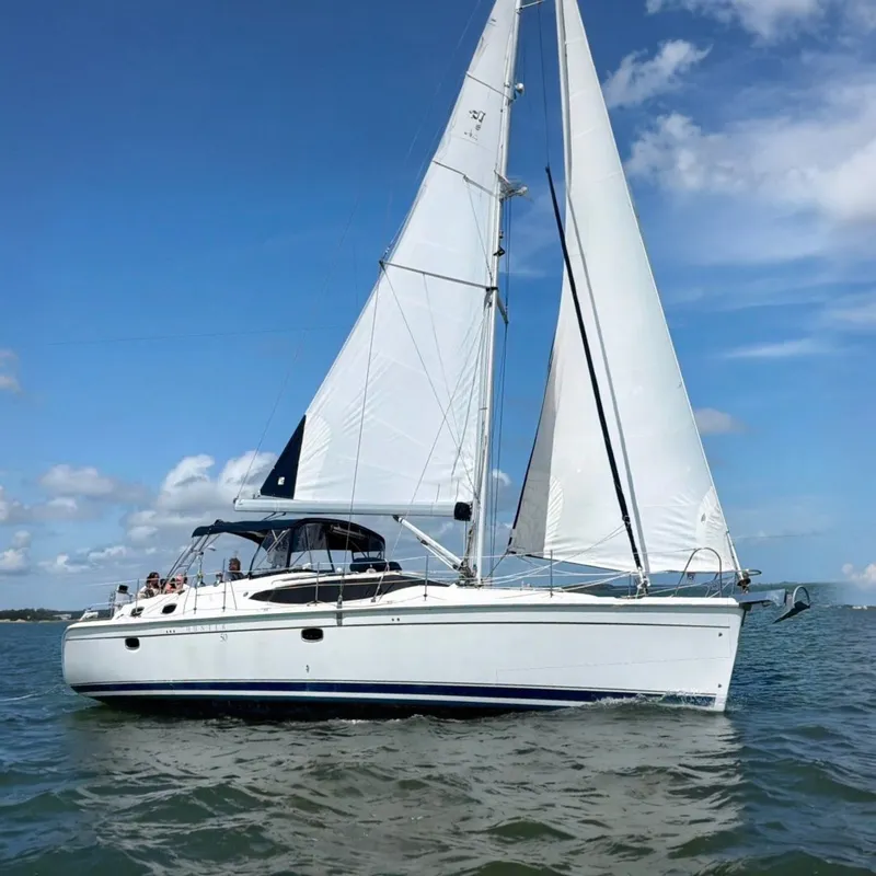 The Image of A 2009 Hunter 50 Center Cockpit yacht sailing on calm waters under a blue sky. - 0