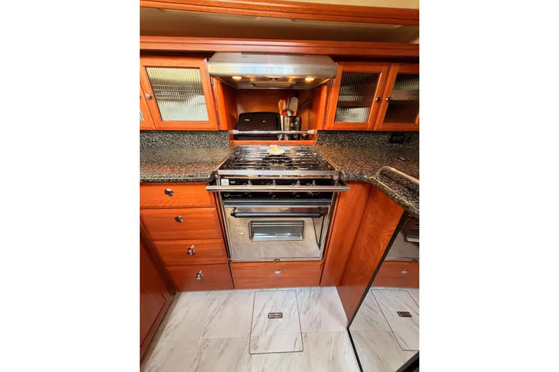 Slide: The Image of 2009 Hunter 50 Center Cockpit yacht kitchen with stove, wooden cabinets, and granite countertops. - 53
