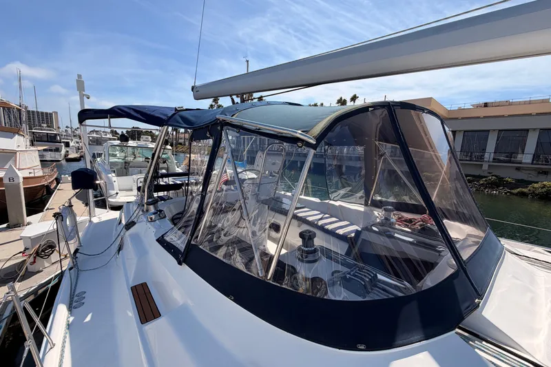 Slide: The Image of 2009 Hunter 50 Center Cockpit sailboat docked at marina, featuring blue canopy and clear enclosure. - 26