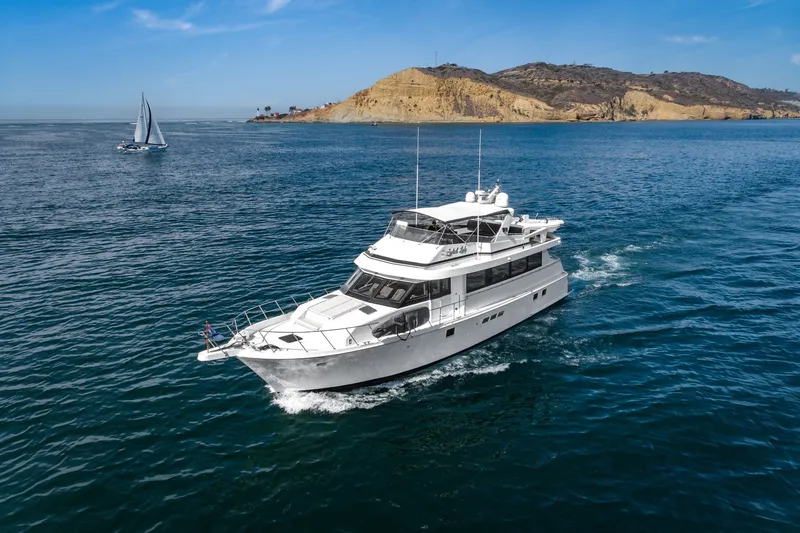 Slide: The Image of 1996 Hatteras 70 Sport Deck Motor Yacht cruising near scenic coastline. - 2