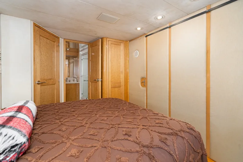 Slide: The Image of Cozy bedroom interior of 1996 Hatteras 70 Sport Deck Motor Yacht with wooden doors and plush bedding. - 60
