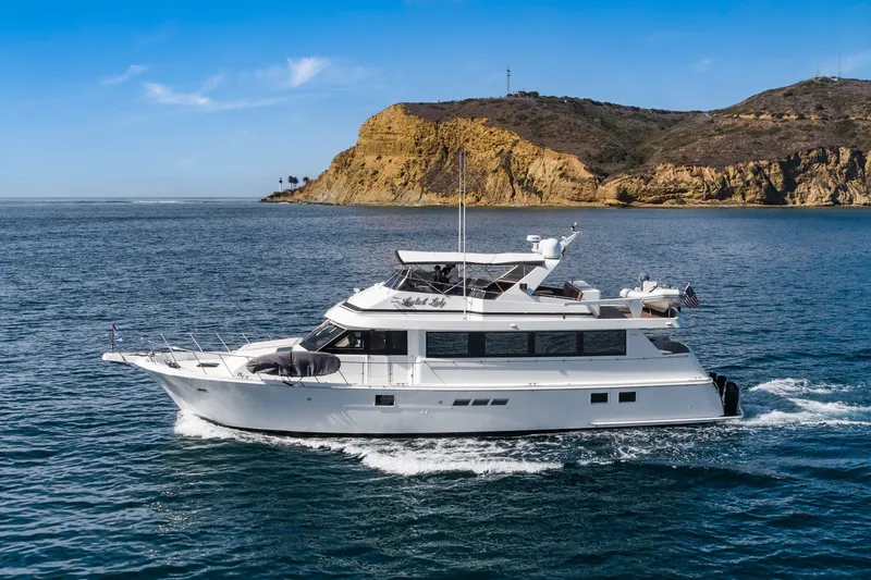 Slide: The Image of 1996 Hatteras 70 Sport Deck Motor Yacht cruising near rocky coastline. - 0