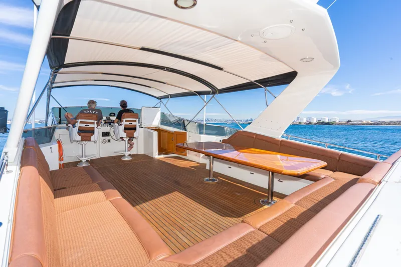 Slide: The Image of 1996 Hatteras 70 Sport Deck Motor Yacht with spacious deck and seating, cruising on open water. - 18
