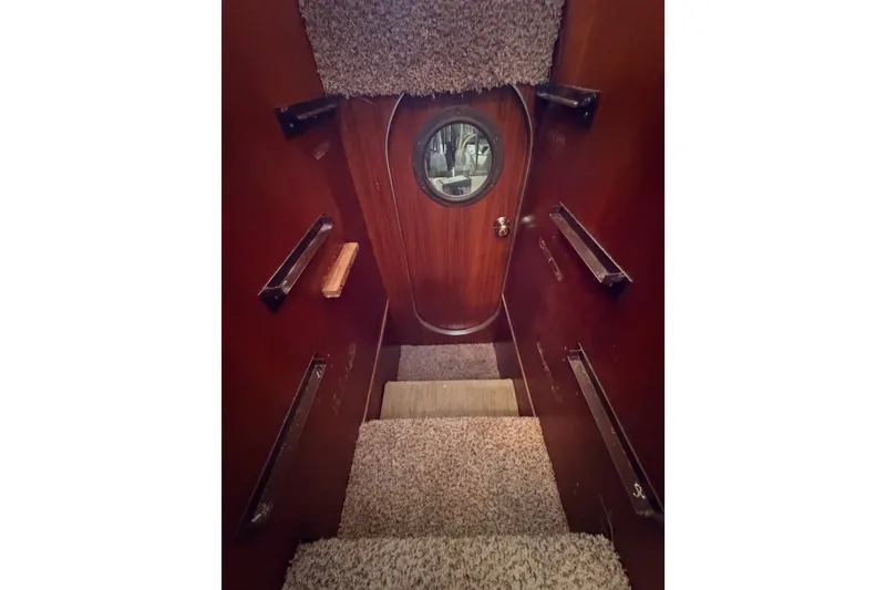Slide: The Image of Interior stairs of 1982 Bertram 54 Convertible yacht with wooden walls and carpeted steps. - 86