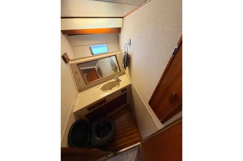 Slide: The Image of 1982 Bertram 54 Convertible yacht bathroom with sink, mirror, and wooden accents. - 74