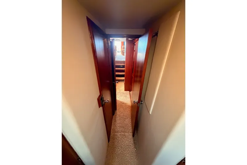 Slide: The Image of Narrow hallway inside 1982 Bertram 54 Convertible yacht with wooden doors and carpeted floor. - 73