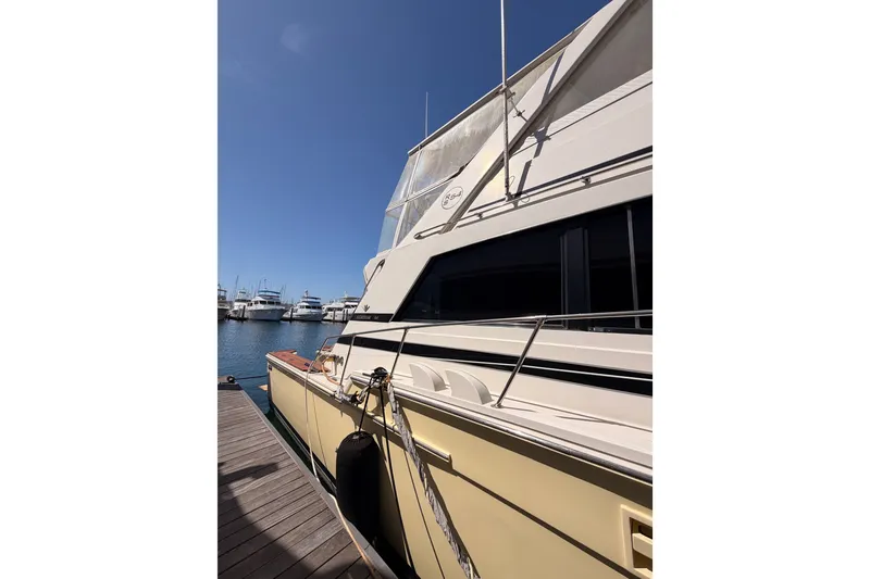 Slide: The Image of 1982 Bertram 54 Convertible yacht docked at marina under clear blue sky. - 13
