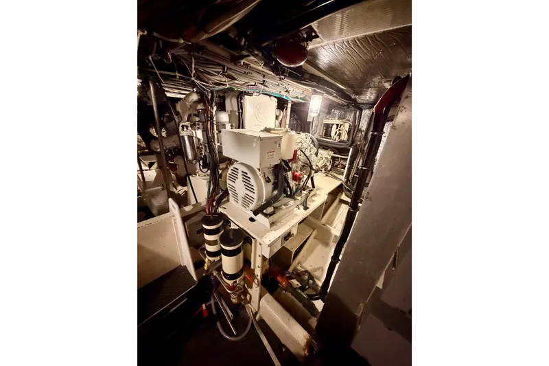 Slide: The Image of Engine room of a 1982 Bertram 54 Convertible yacht, showcasing mechanical components and wiring. - 89