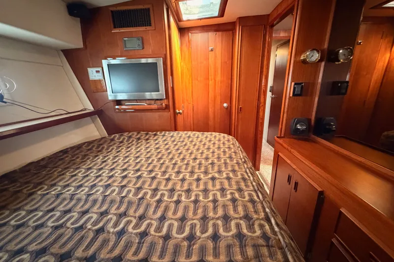 Slide: The Image of Interior of 1982 Bertram 54 Convertible yacht with wood paneling and patterned bedding. - 83