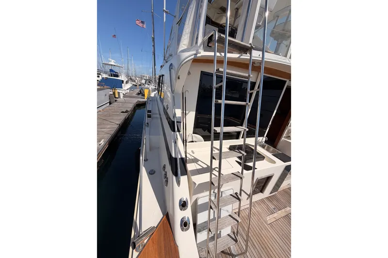 Slide: The Image of 1982 Bertram 54 Convertible yacht docked, featuring sleek design and ladder access. - 19