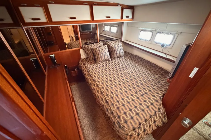 Slide: The Image of Cozy bedroom interior of 1982 Bertram 54 Convertible yacht with patterned bedding and wooden cabinetry. - 77
