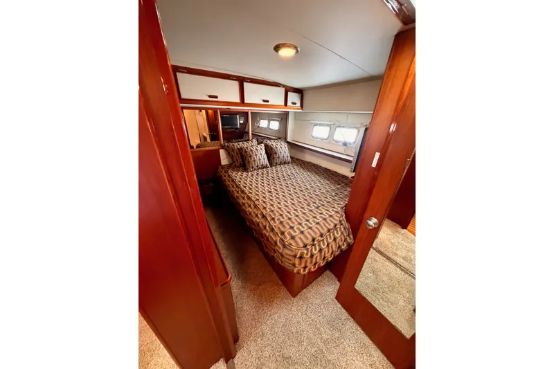 Slide: The Image of Interior cabin of 1982 Bertram 54 Convertible yacht with patterned bedding and wood accents. - 76