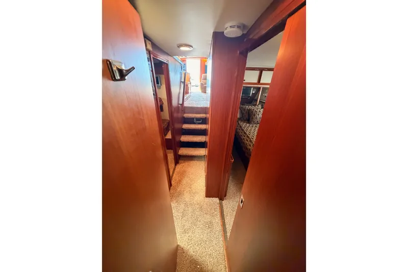 Slide: The Image of Interior hallway of 1982 Bertram 54 Convertible yacht, featuring wood paneling and carpeted flooring. - 75
