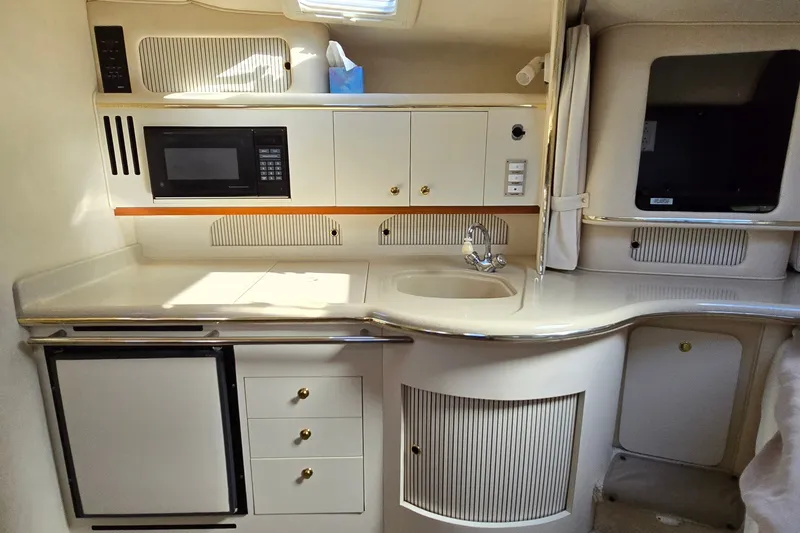 Slide: The Image of 2001 Sea Ray Sundancer 310 yacht kitchen with microwave, sink, and storage cabinets. - 24