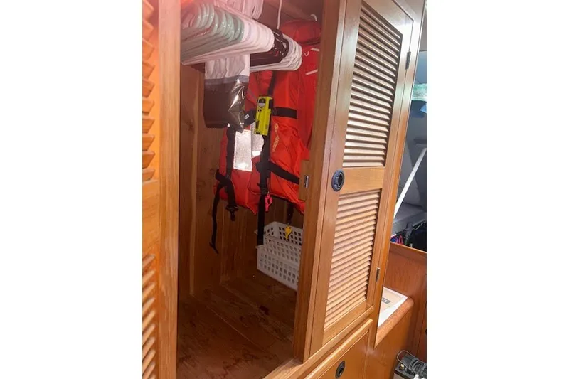 Slide: The Image of Wooden closet interior on a 2004 Manta 42 MkII yacht, featuring life jackets and hangers. - 20