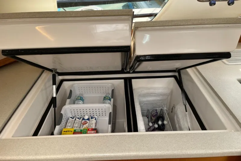 Slide: The Image of Open refrigerator compartments on a 2004 Manta 42 MkII yacht, stocked with beverages and snacks. - 44